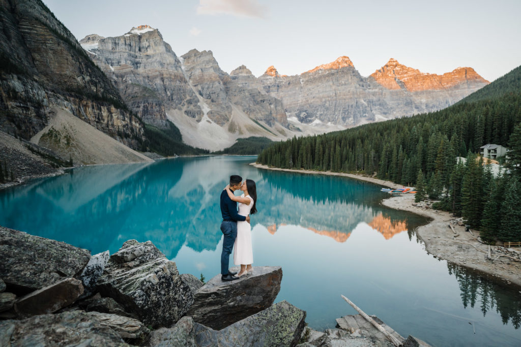 Engaged couple embraces as sunrise lights up the Valley of the 10 Peaks