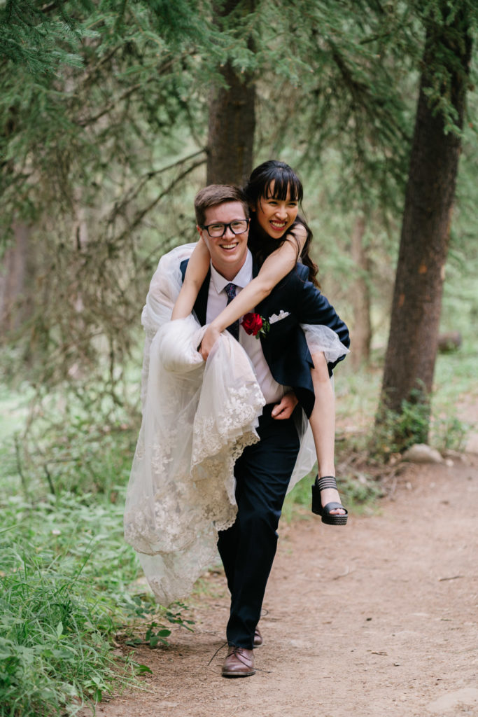 Groom gives bride piggyback in Jasper National Park