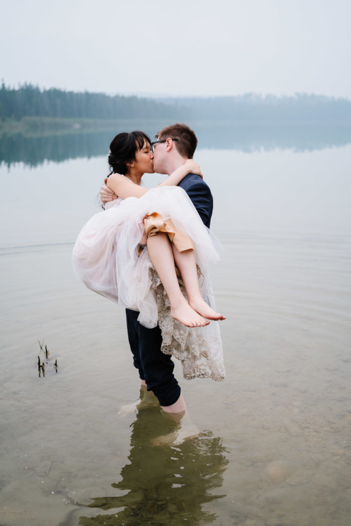 groom holds bride in water in Patricia Lake