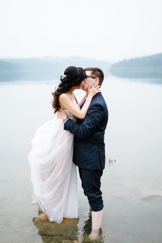 Bride and groom kiss in Patricia Lake in Jasper
