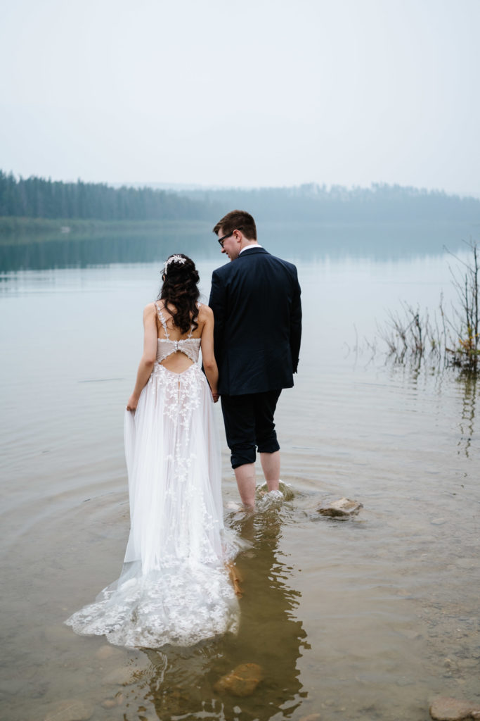 Bride and groom walk in water in Jasper National Park elopement