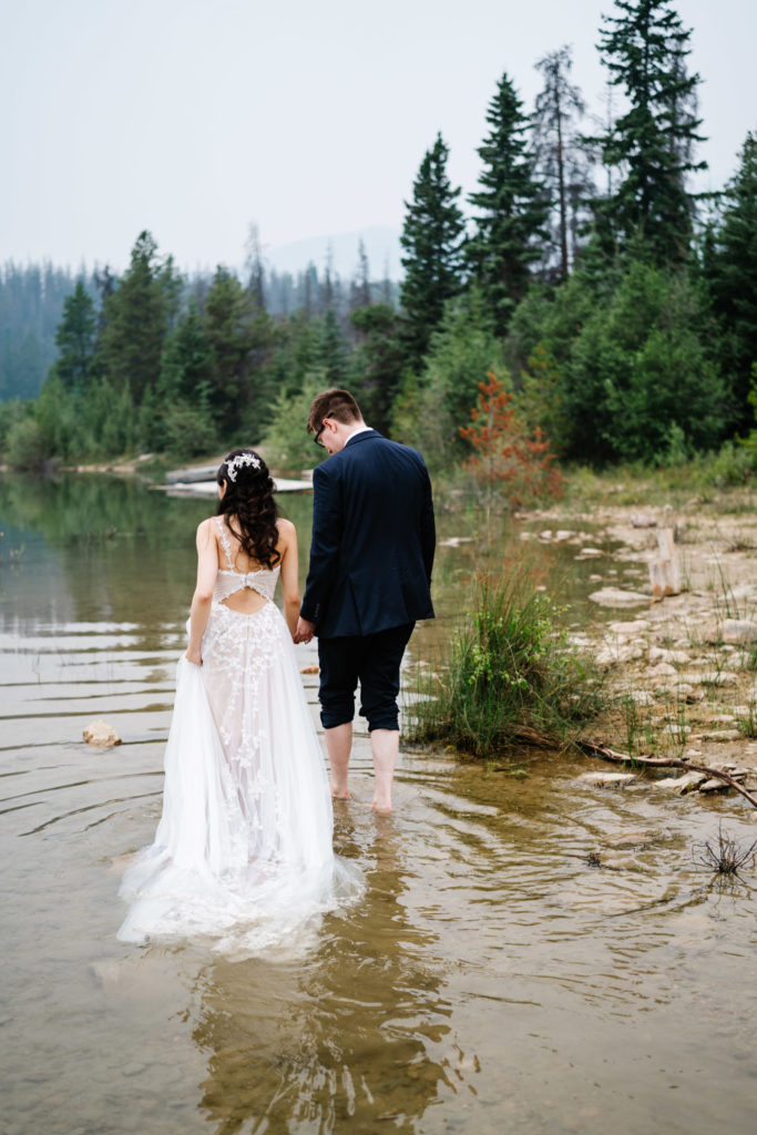 Eloping couple walks in the water in Jasper National Park