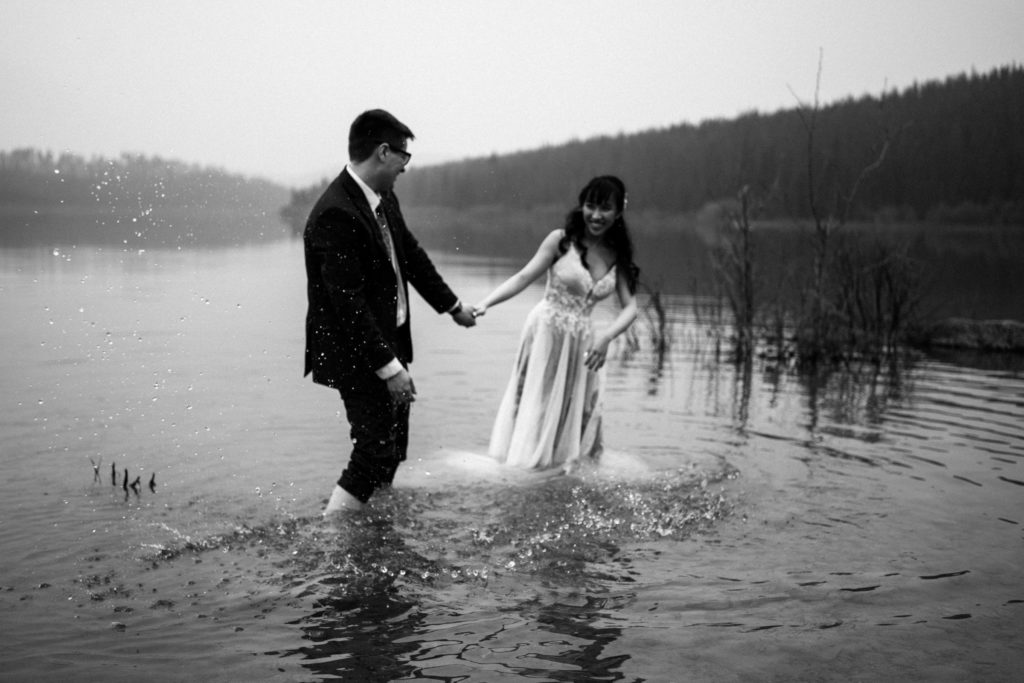 Bride and groom splash each other in Patricia Lake in black and white