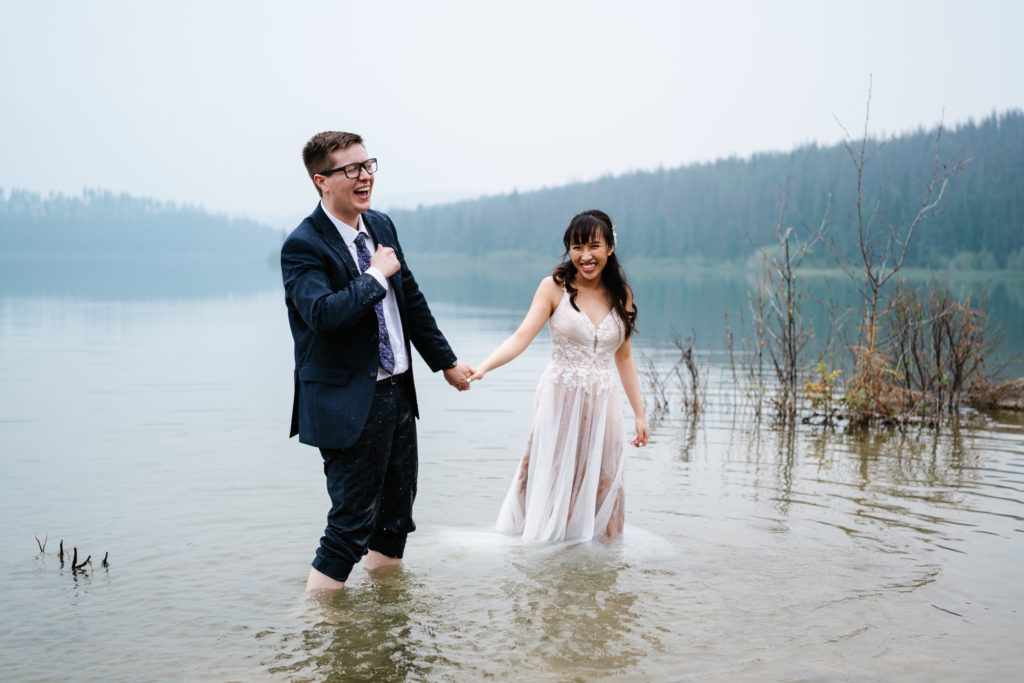 groom laughs while playing in the water in Jasper National Park