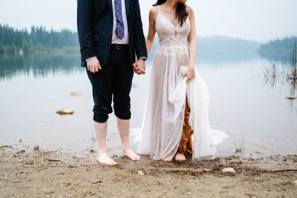 barefoot bride and groom on shore in Jasper National Park