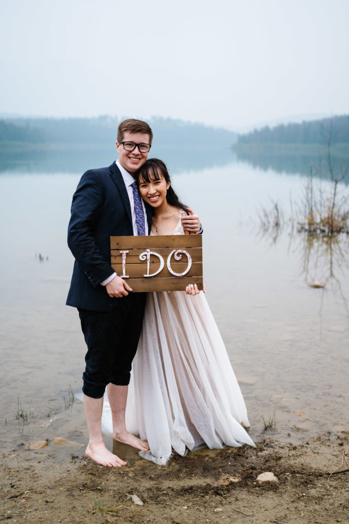 Bride and groom hold I do sign in Jasper National Park