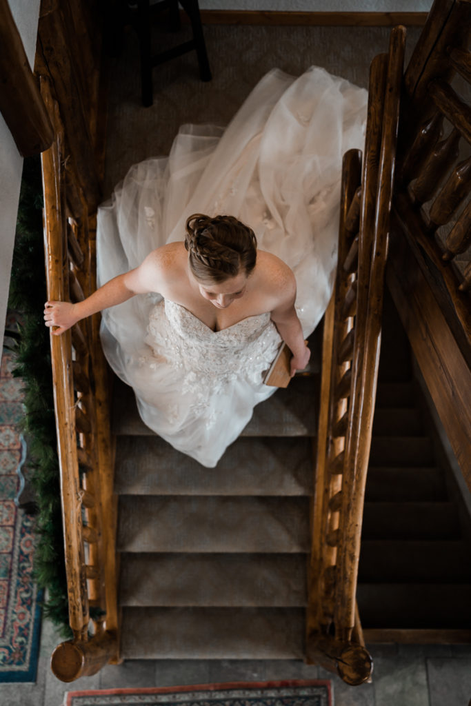 A bride walks down the stairs for the first look at A Bear and Bison Inn in Canmore Alberta