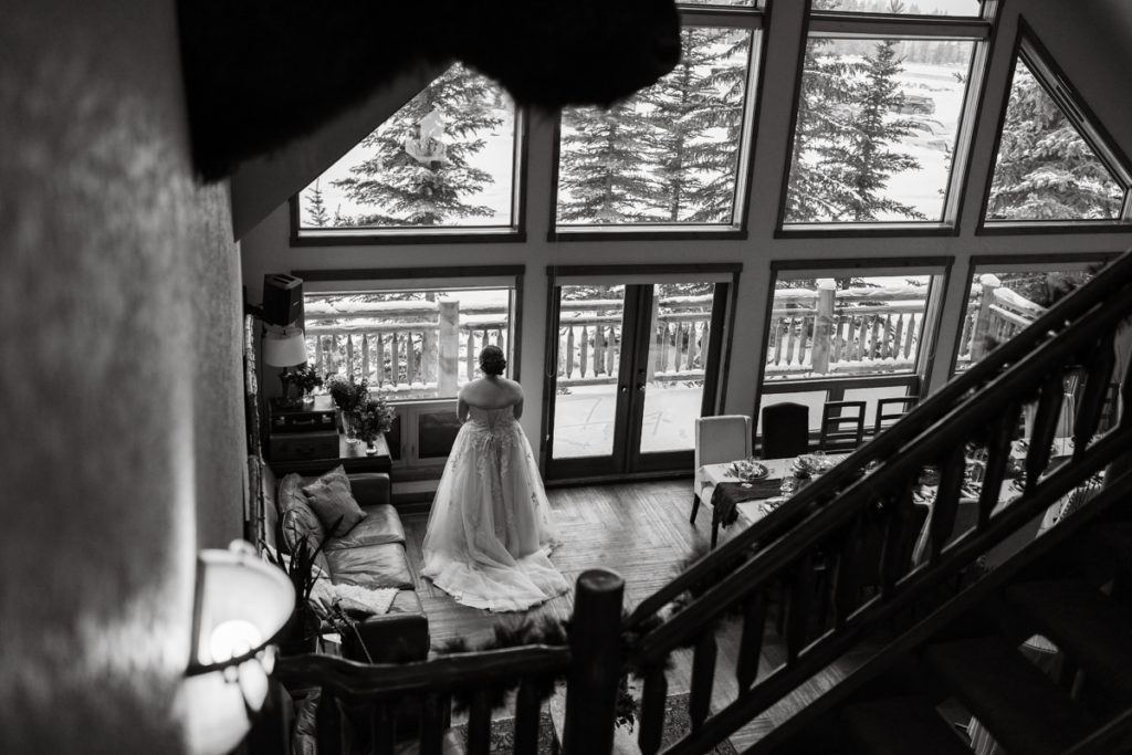Bride looks out the window in the main room at A Bear and Bison Inn in Canmore. 