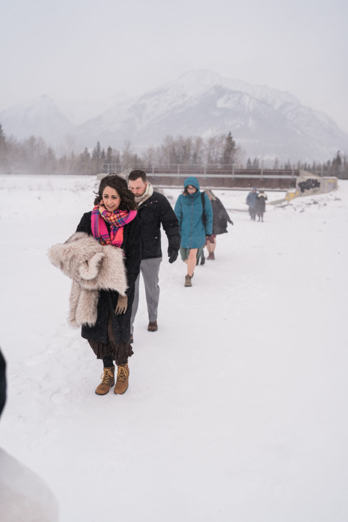 Family walks through snow on cold day for intimate lgbtq+ wedding. 