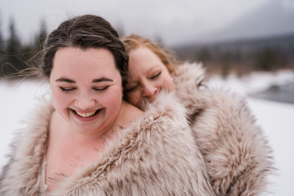 Close up of two brides snuggling during winter wedding. 