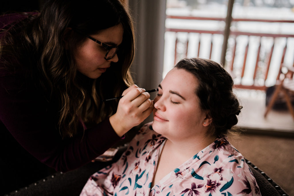 A bride sits and gets her makeup done at A Bear and Bison Inn. 