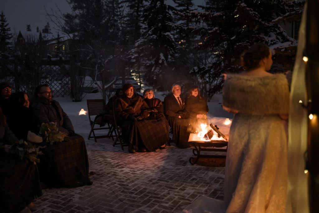 Families sit around a campfire at a Bear and Bison Inn for outdoor winter ceremony