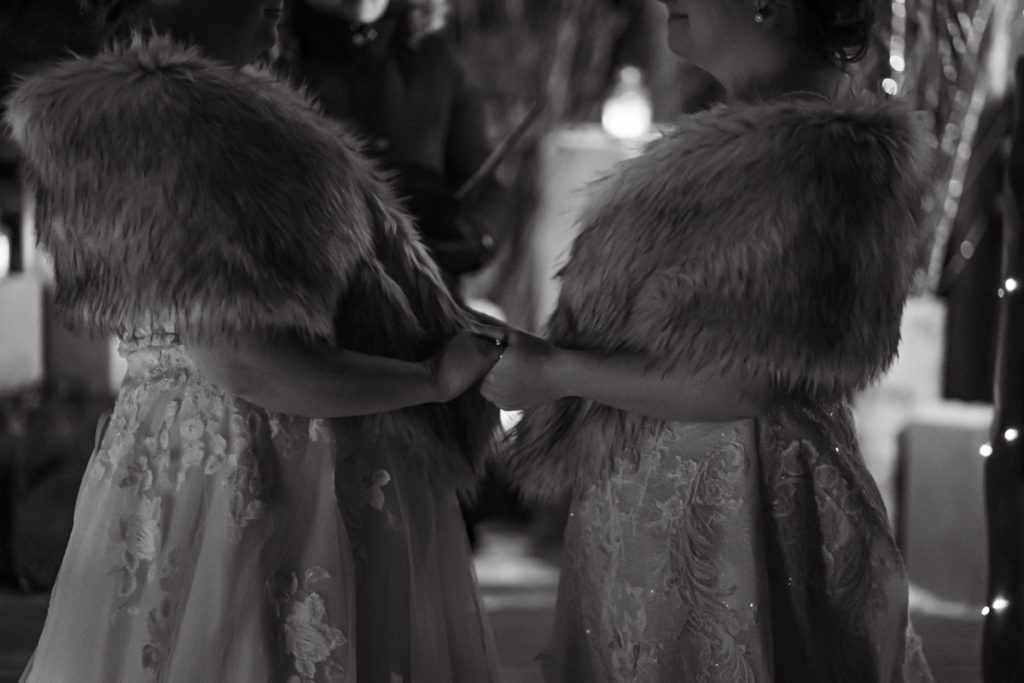 Black and white photo of two brides holding hands during ceremony. 
