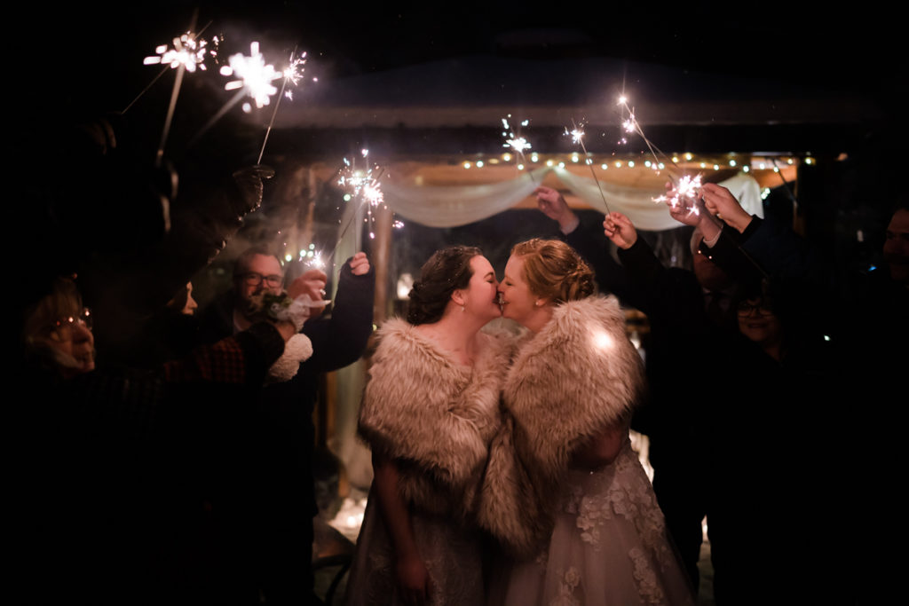 two brides wearing fur shawls during sparkler exit at winter wedding
