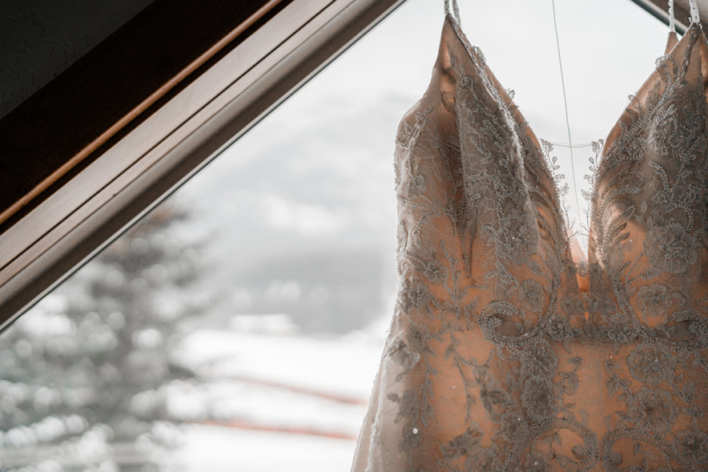 Close up shot of the bodice of wedding dress hanging in front of window in Canmore.