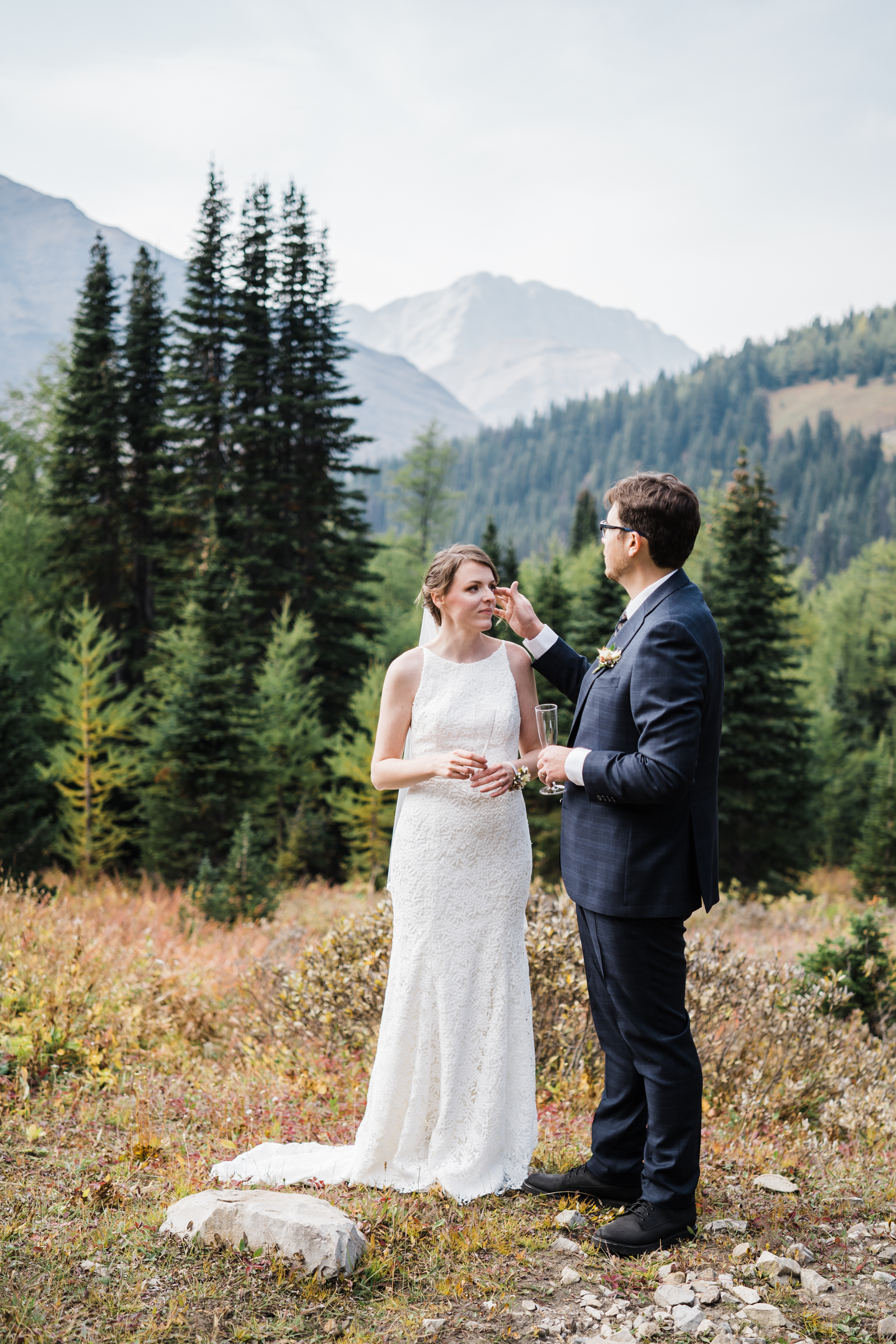 Groom brushes hair out of the brides face with the mountains in the background. 