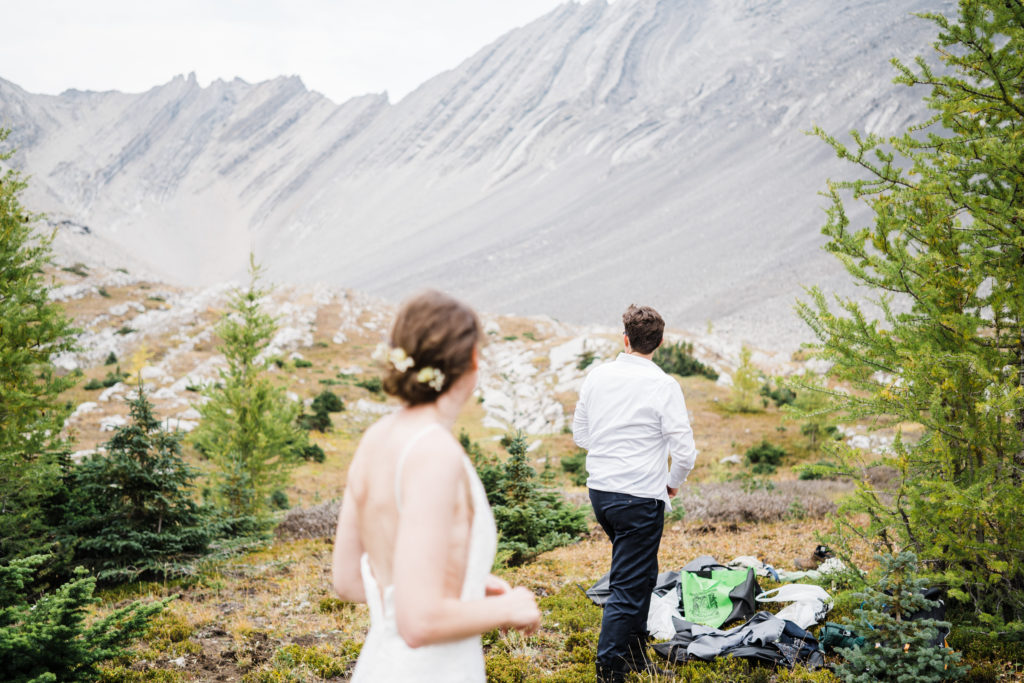 Bride and groom change into wedding clothes during their hiking elopement.