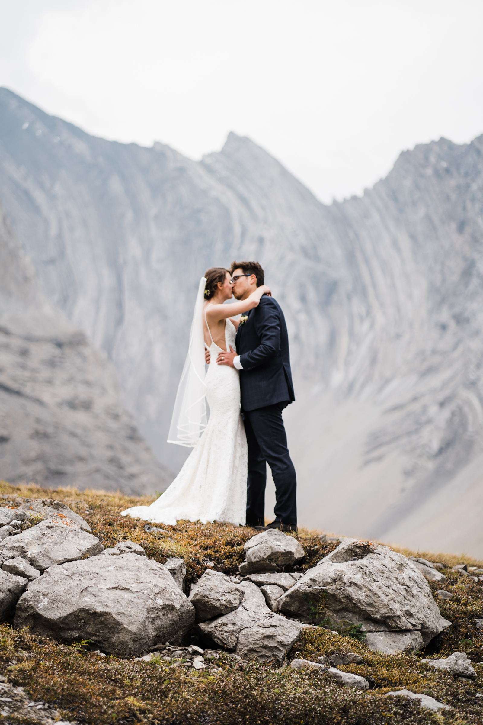 Bride and groom kiss with towering mountains in the background in Arethusa Cirque in Kananaskis. 