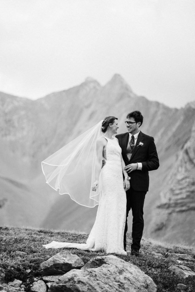 Black and white image of bride and groom laughing during hiking elopement. 