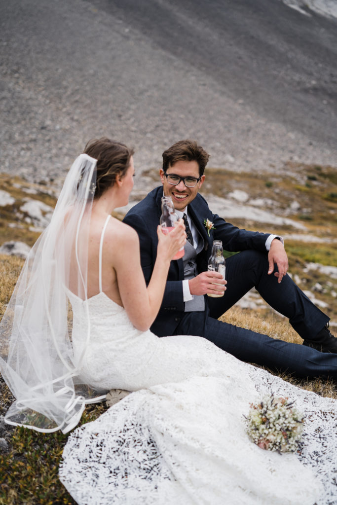 Groom laughs at bride while they are sitting sharing lemonade. 