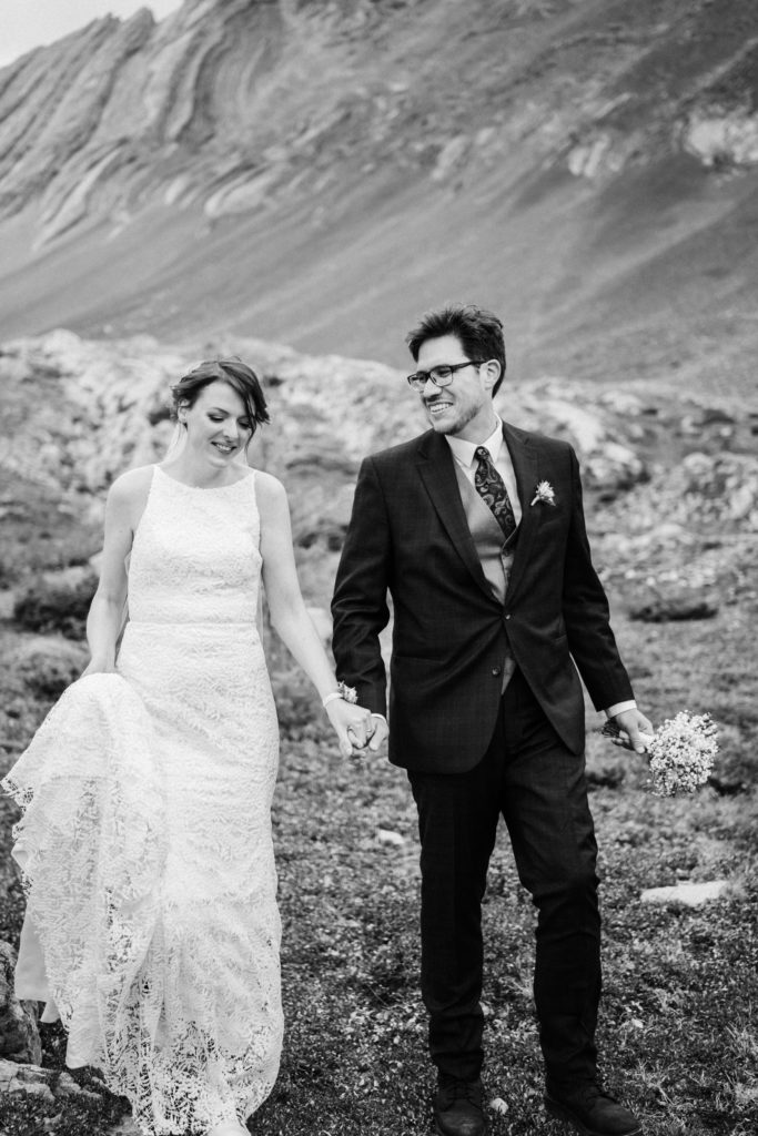 Black and white photo of bride and groom laughing while walking together. 