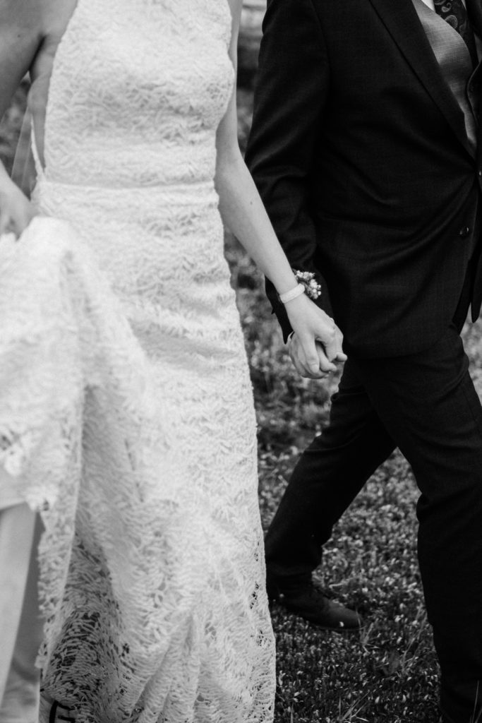Black and white photo of bride and grooms hands during hiking elopement.