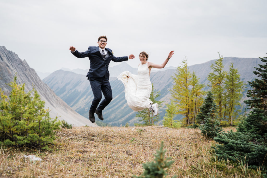 Bride and groom leap into the air during their hiking elopement in Kananaskis, Alberta. 