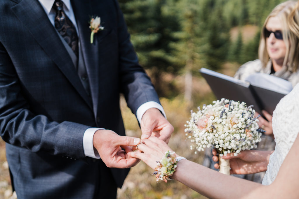 Groom places ring on brides finger during Kananaskis hiking elopement.