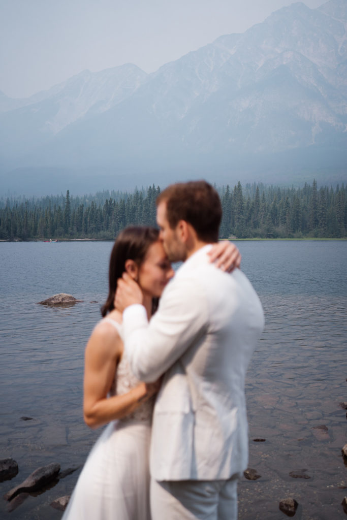 Bride and groom kiss while not in focus at Jasper National Park