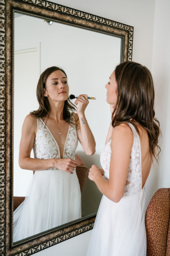 Bride puts her makeup on in mirror in Jasper National Park. 