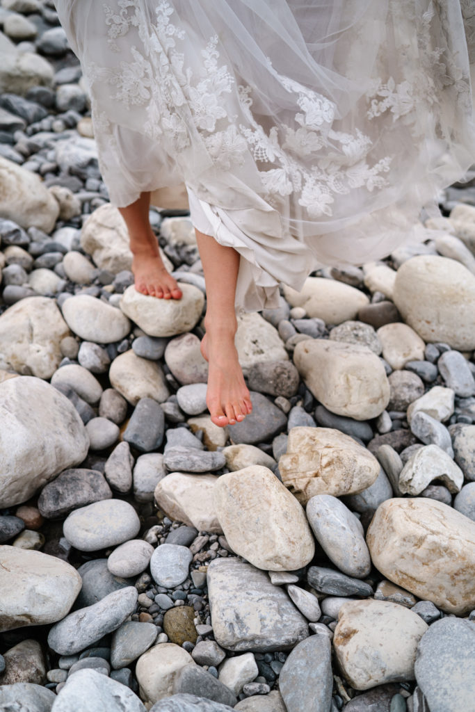 Barefoot brides feet walk along rocks in Jasper National Park. 