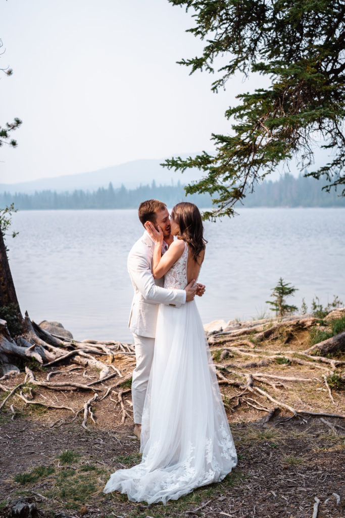 Bride and groom kissing in front of the river in Jasper National Park.