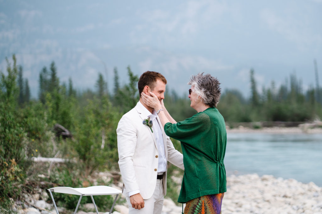 grooms mom holds his face after wedding ceremony in Jasper National Park.