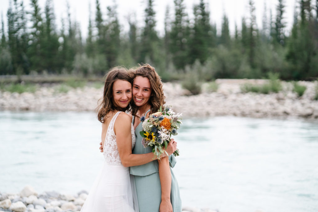 bride embraces sister next to the snaring river 