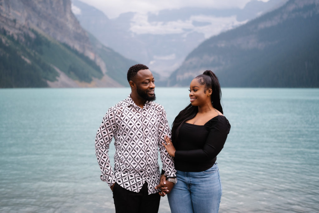 Couple holds hands and looks at each other in Banff National Park