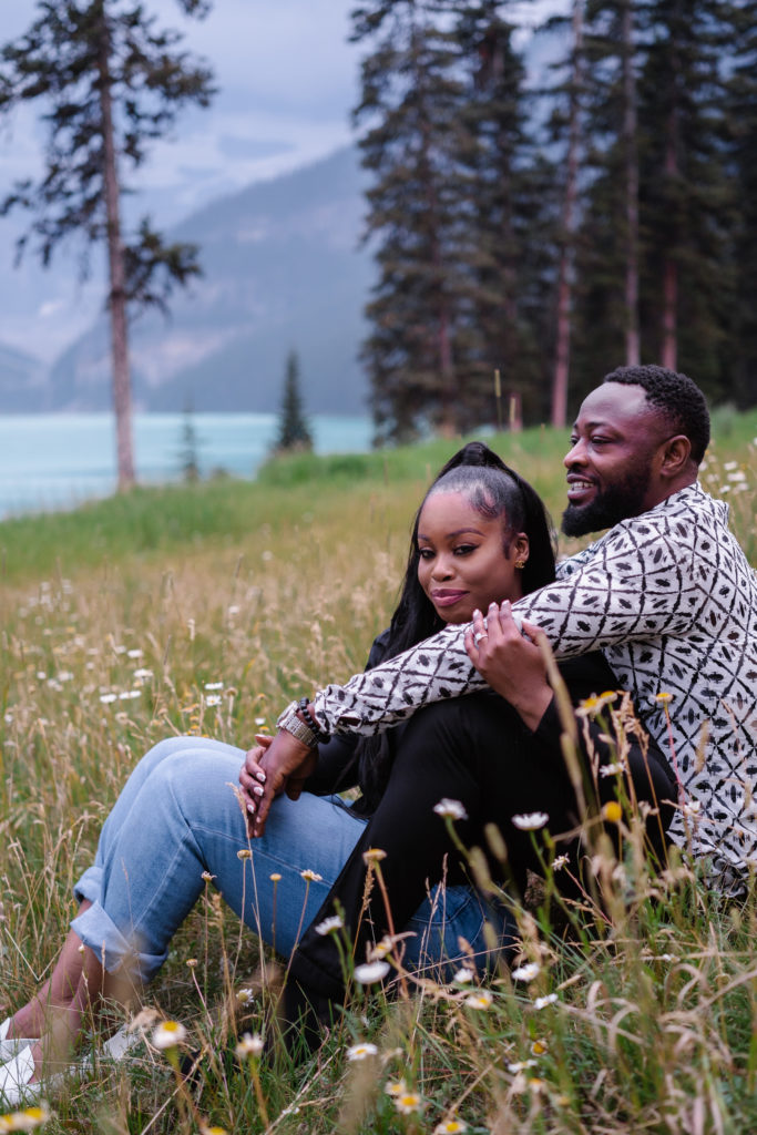 Couple sits in the wildflowers at Lake Louise.