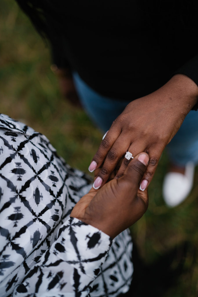 Man slides engagement ring on womans finger. 