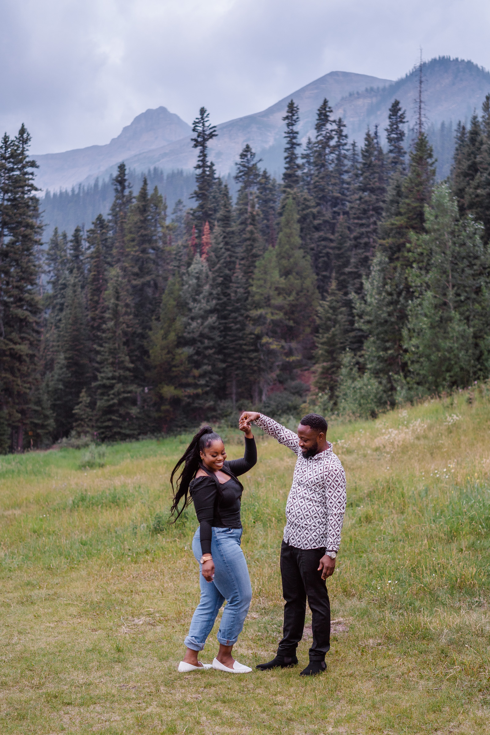 Couple dances together in flowers at Lake Louise after proposal. 