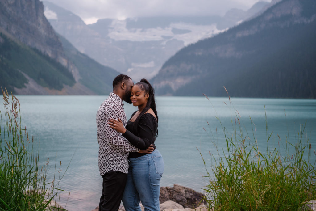 Newly engaged couple have quiet moment together in front of Lake Louise. 