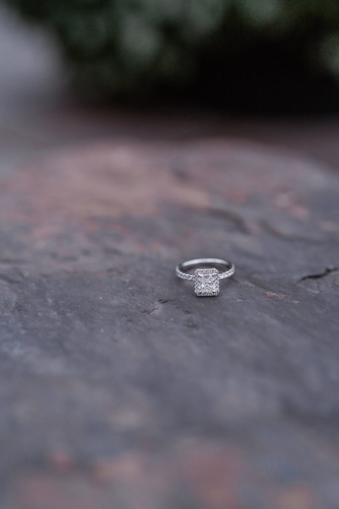 Close up of diamond ring on rock after surprise Lake Louise proposal. 