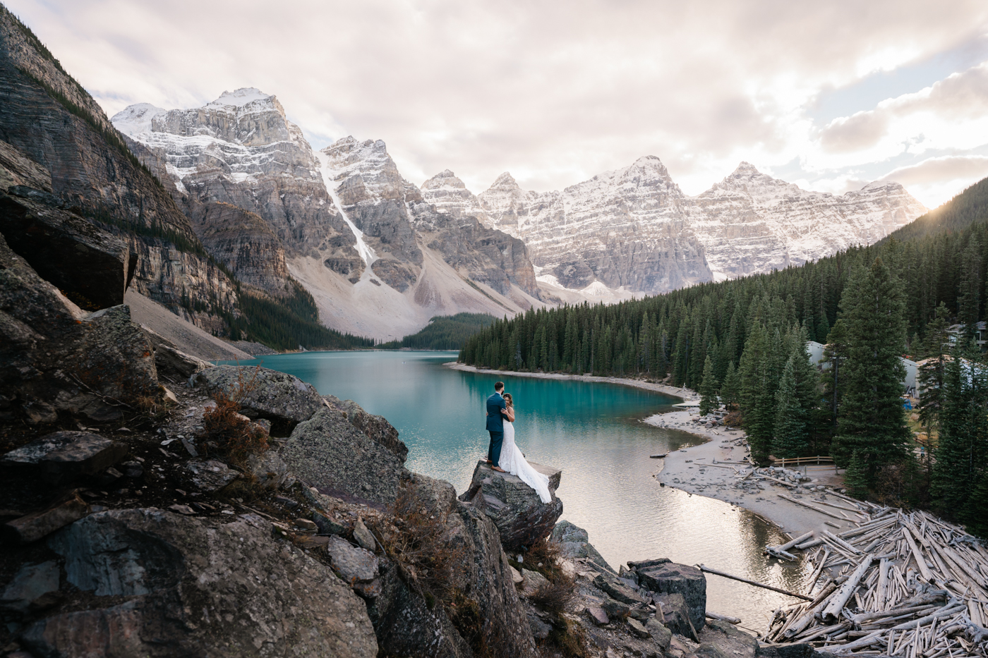 Bride and groom embrace at Moraine lake during sunset