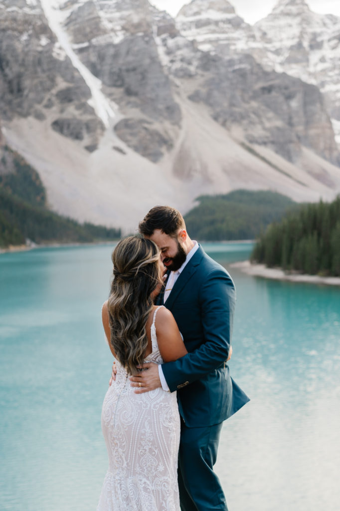 Bride and groom touch foreheads in front of Moraine lake