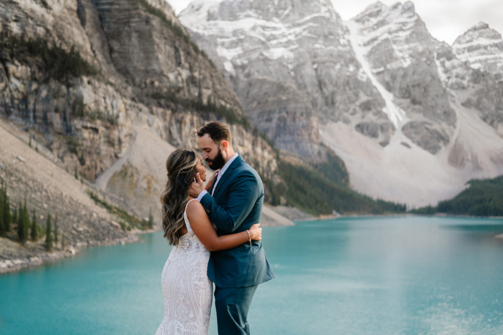 Groom holds brides face and leans in for a kiss in Banff National Park. 
