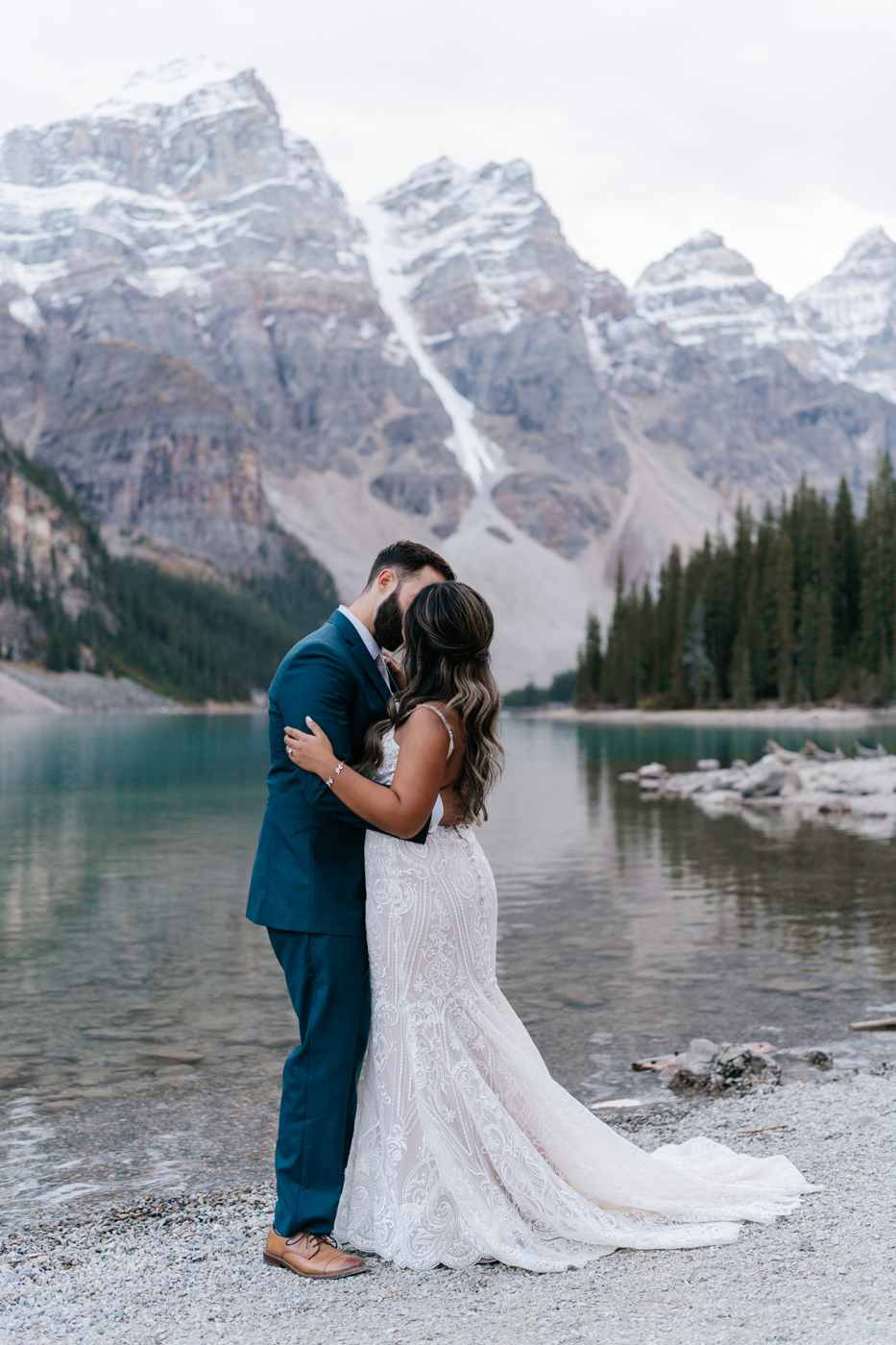 Bride and groom kiss infront of reflection at Moraine Lake
