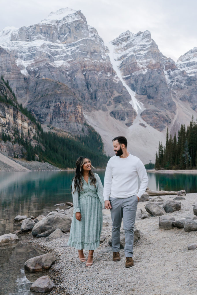 Couple holds hands and walks towards the camera at Moraine Lake 