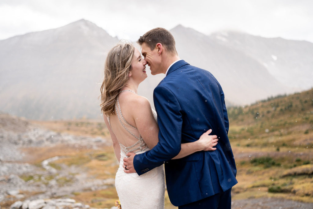 Bride and groom smile and kiss during Kananaskis hiking elopement