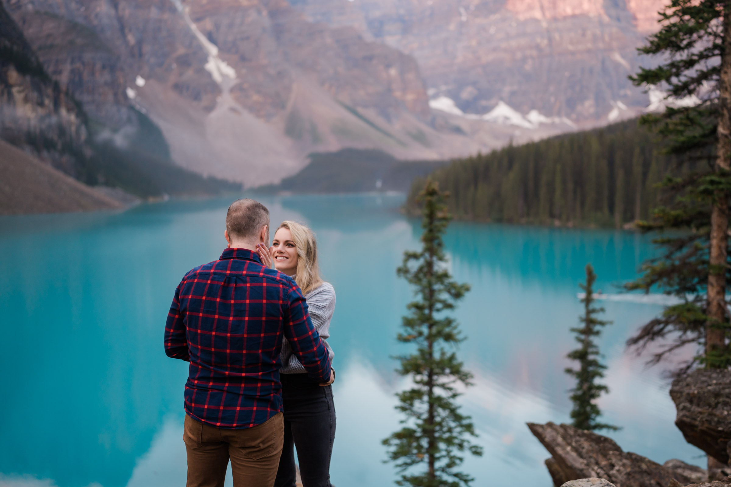 Woman has hands on her boyfriend face as she says yes to his proposal in Banff. 