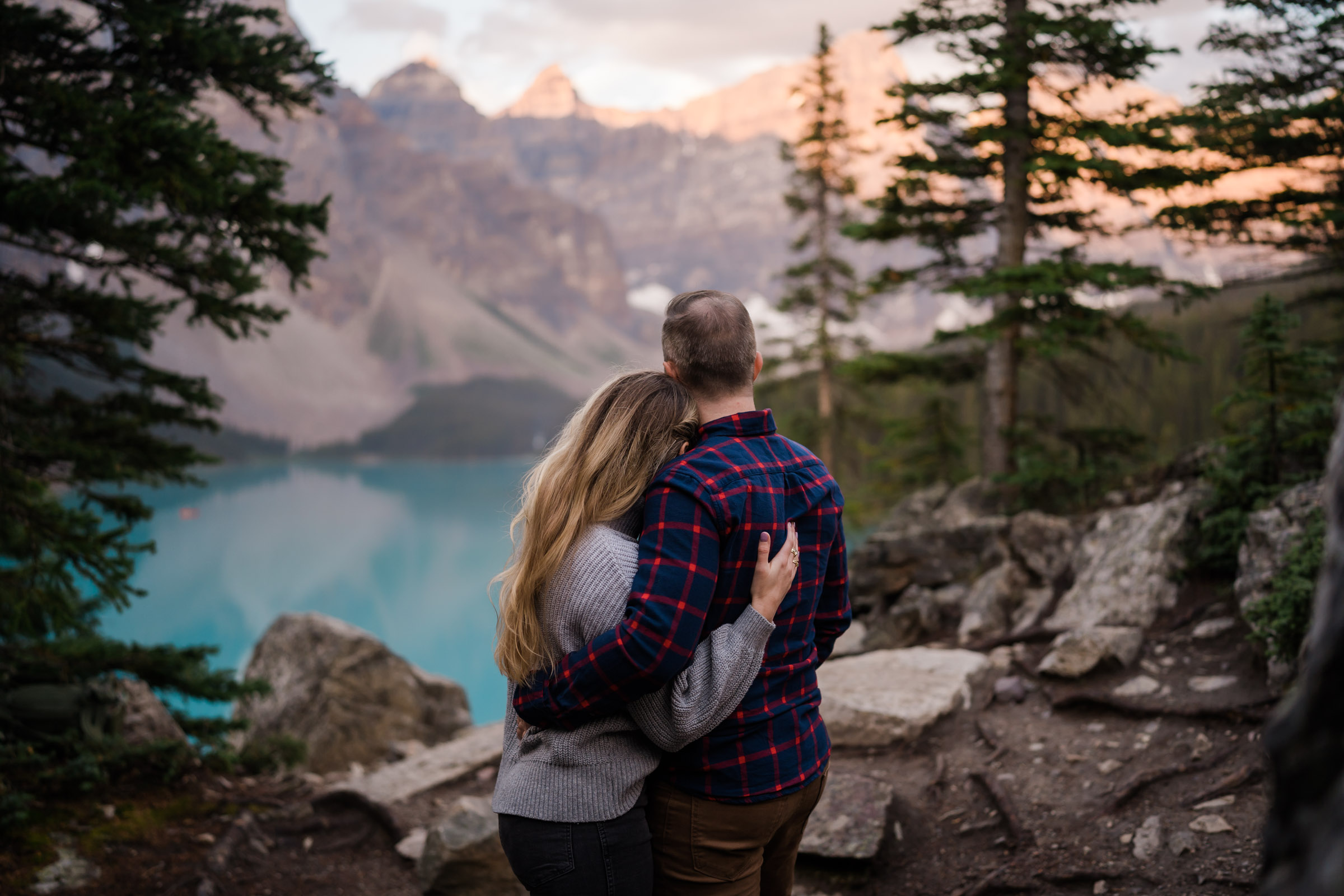 Couple embraces and watches the sun come up over Moraine Lake.