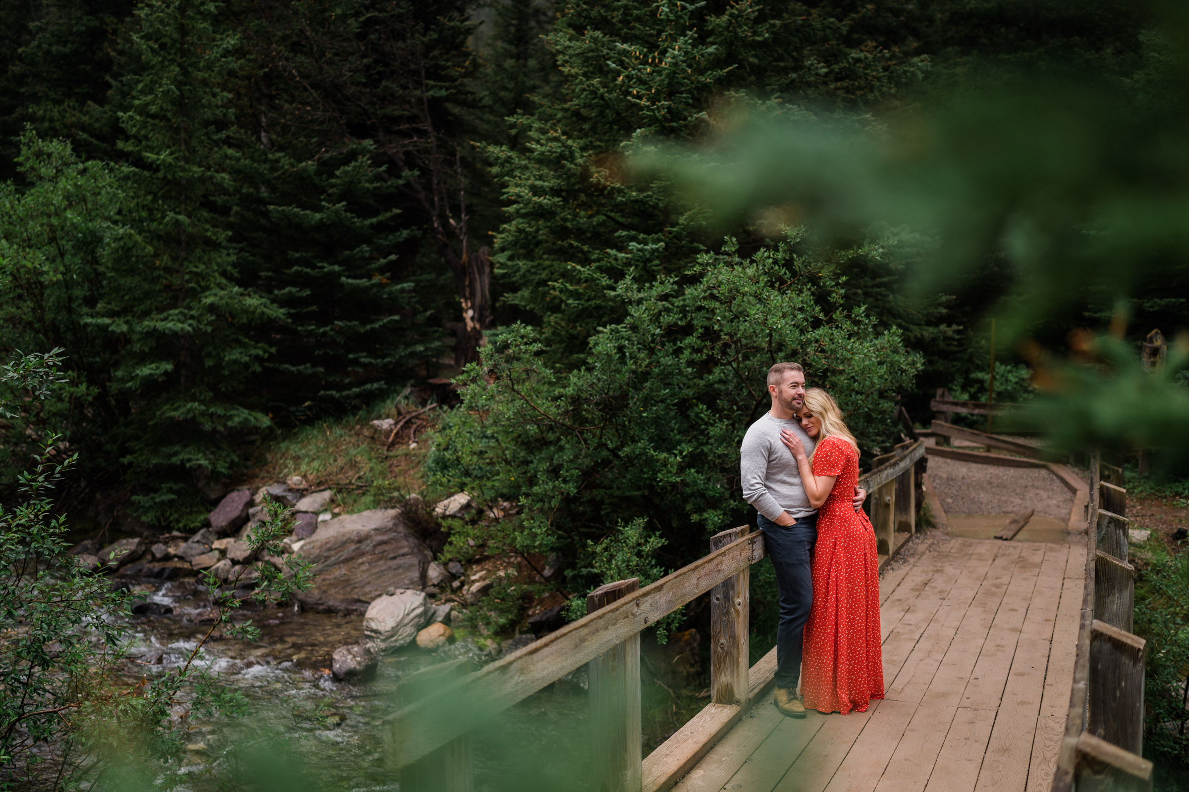 Couple cuddles on wooden dock at Moraine Lake during Banff Engagement Photos. 