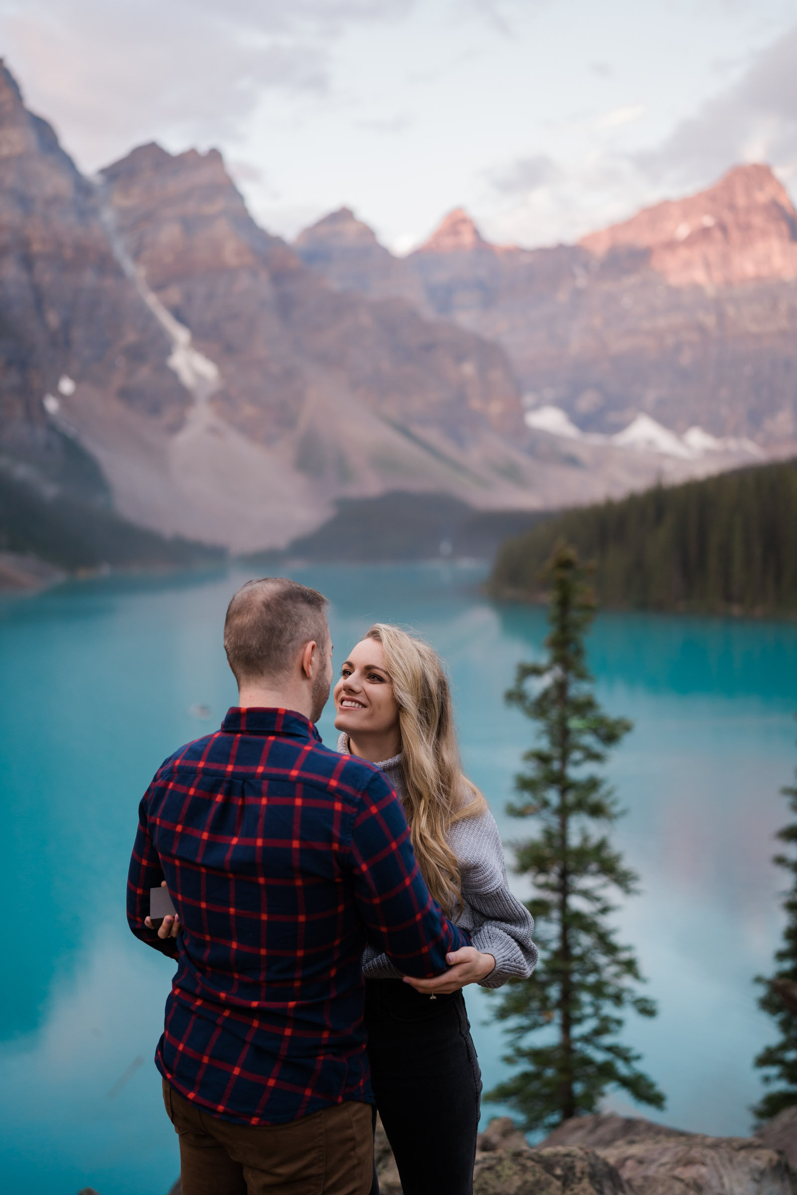 Man and women embrace in front of Moraine Lake after a proposal. 